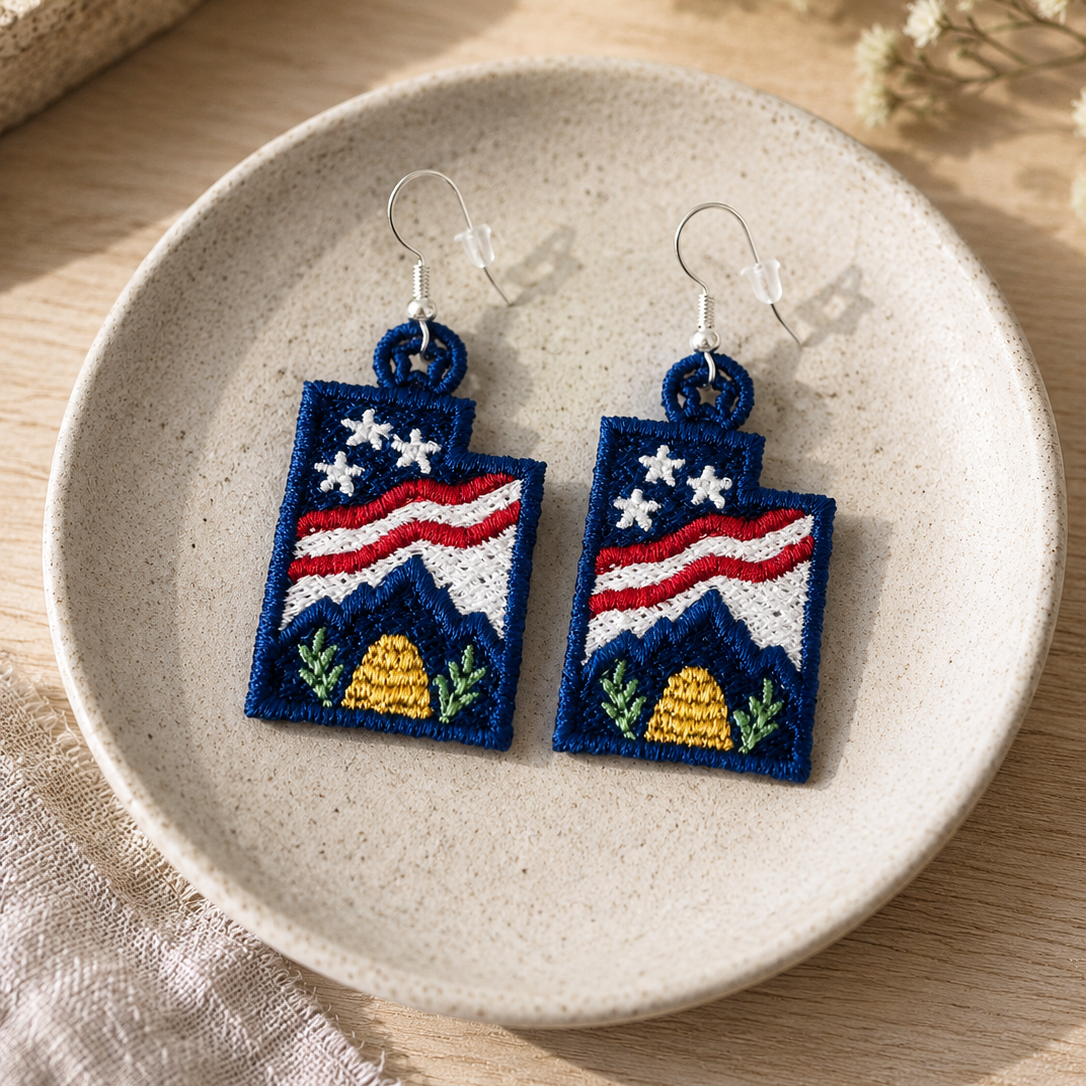 Embroidered earrings with American flag design on a ceramic plate.