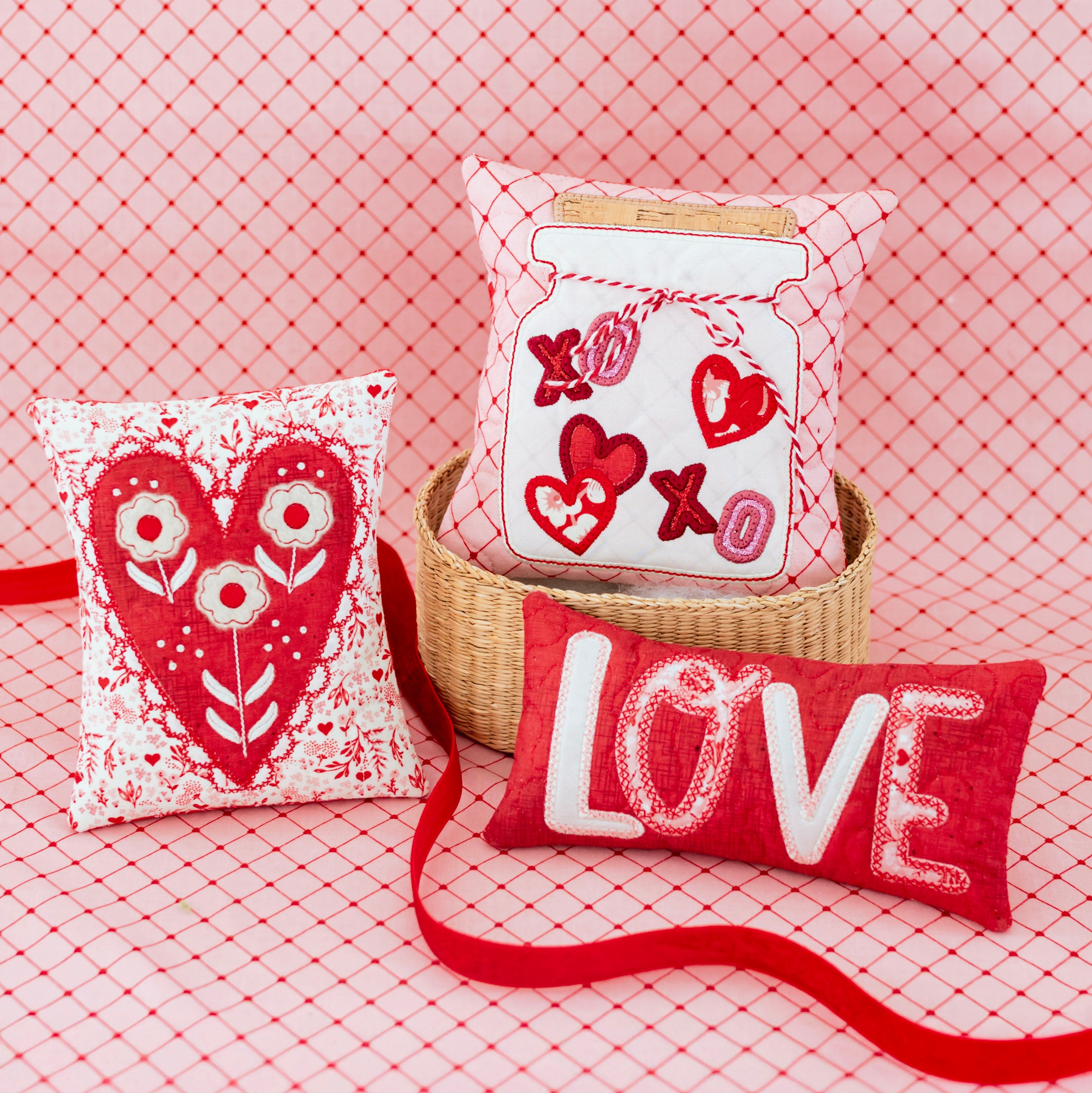 Decorative pillows with heart and 'LOVE' designs on a pink textured background