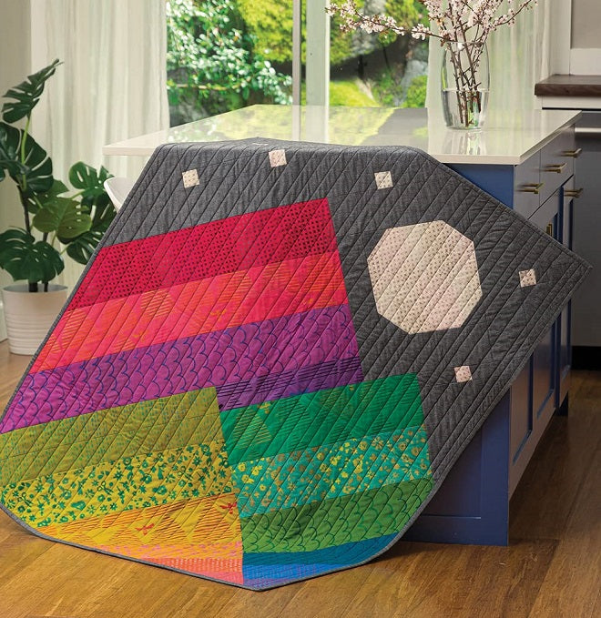 Colorful mountain and moon quilt hanging from a countertop