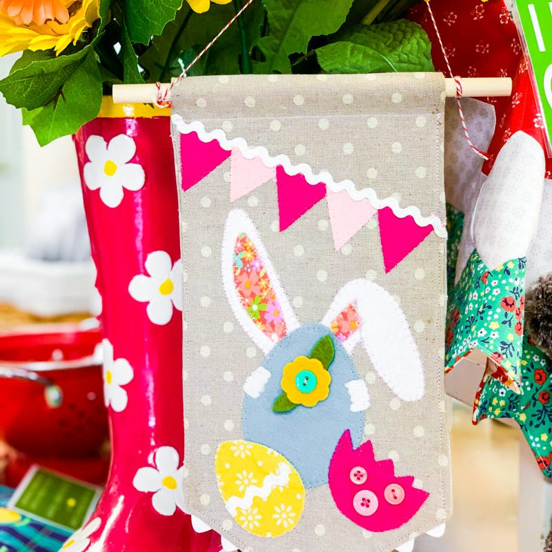 Appliqué bunny hiding behind Easter eggs on a small banner