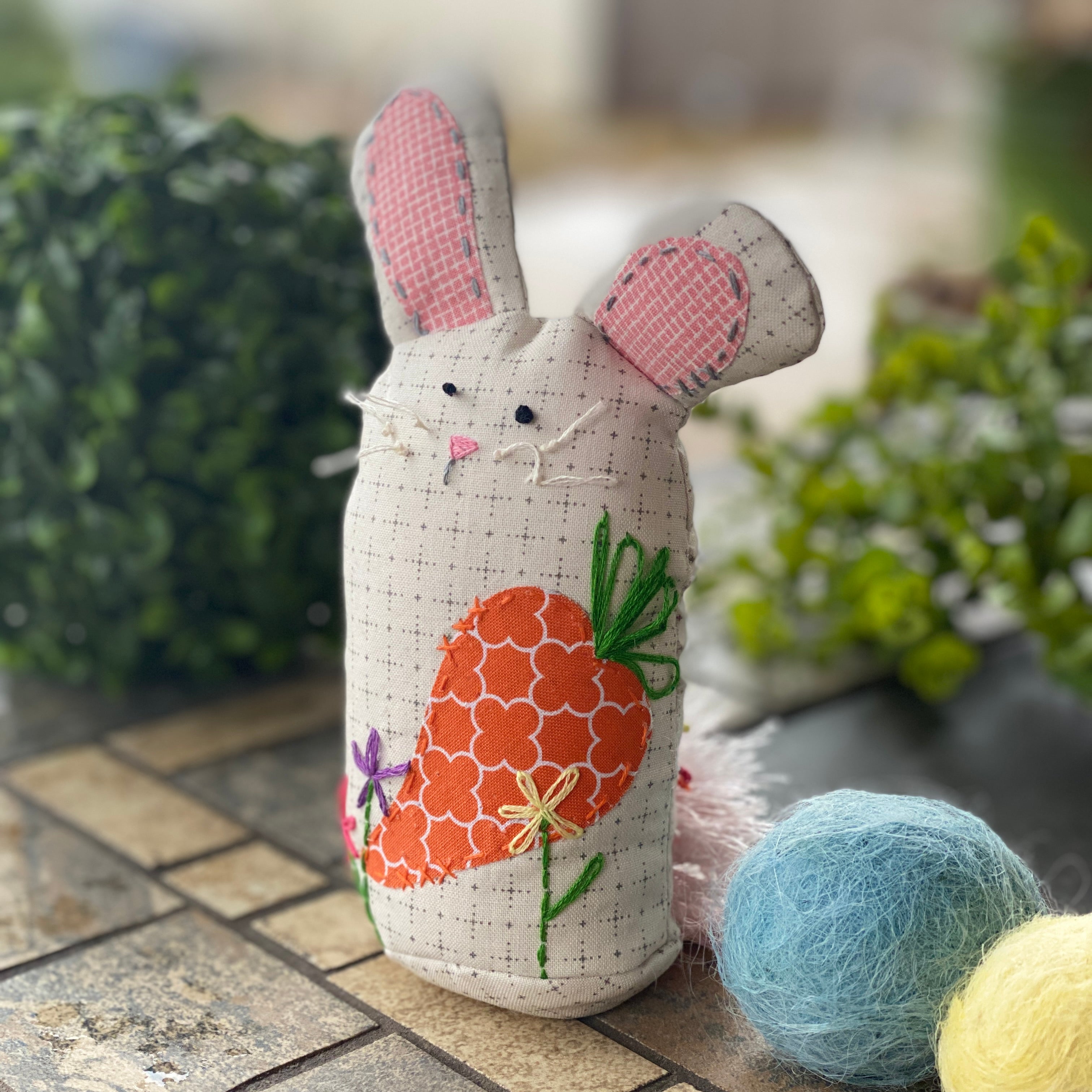 A bunny-shaped pincushion with hand-embroidered details.