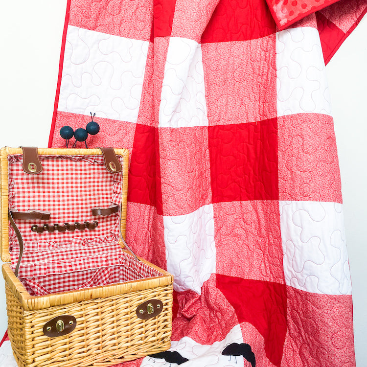 Red Gingham Family Reunion Picnic Quilt beside a picnic basket