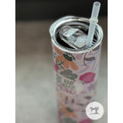 Colorful tumbler with floral design and straw on a neutral background