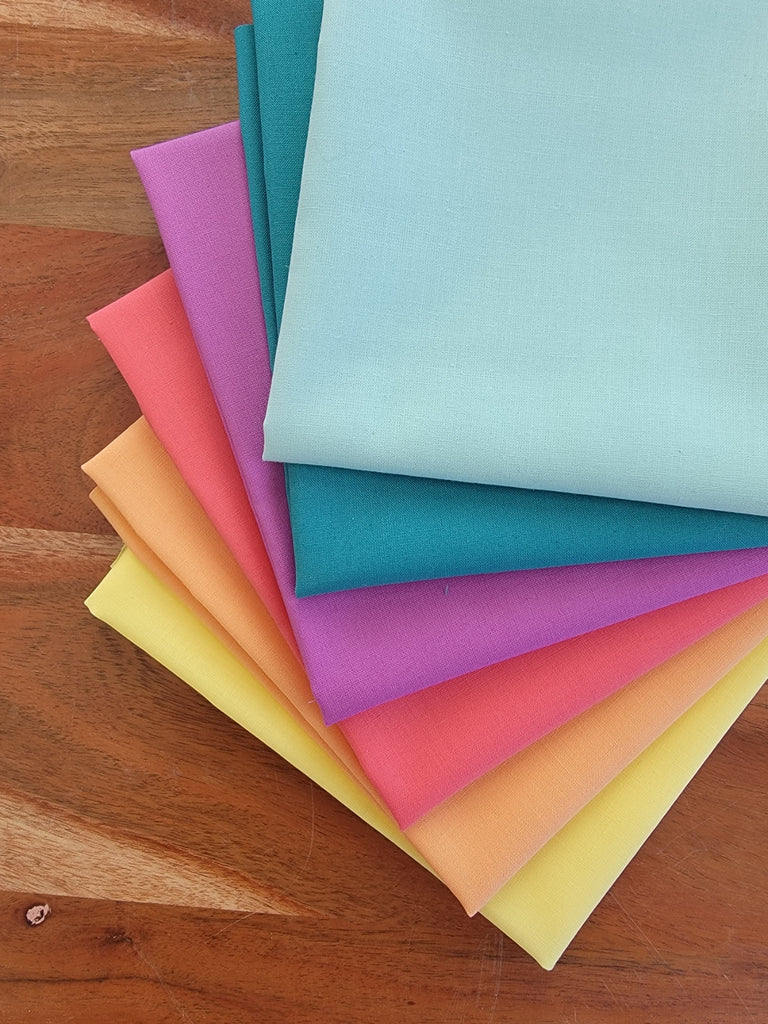 Six fat quarters of solid fabric in rainbow colors. 