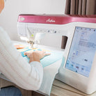 Person using a sewing machine with a digital display on a table.