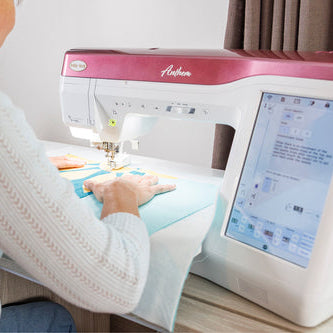 Person using a sewing machine with a digital display on a table.
