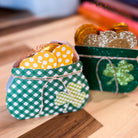 Two small green pots filled with gold coins and decorative items on a wooden surface.