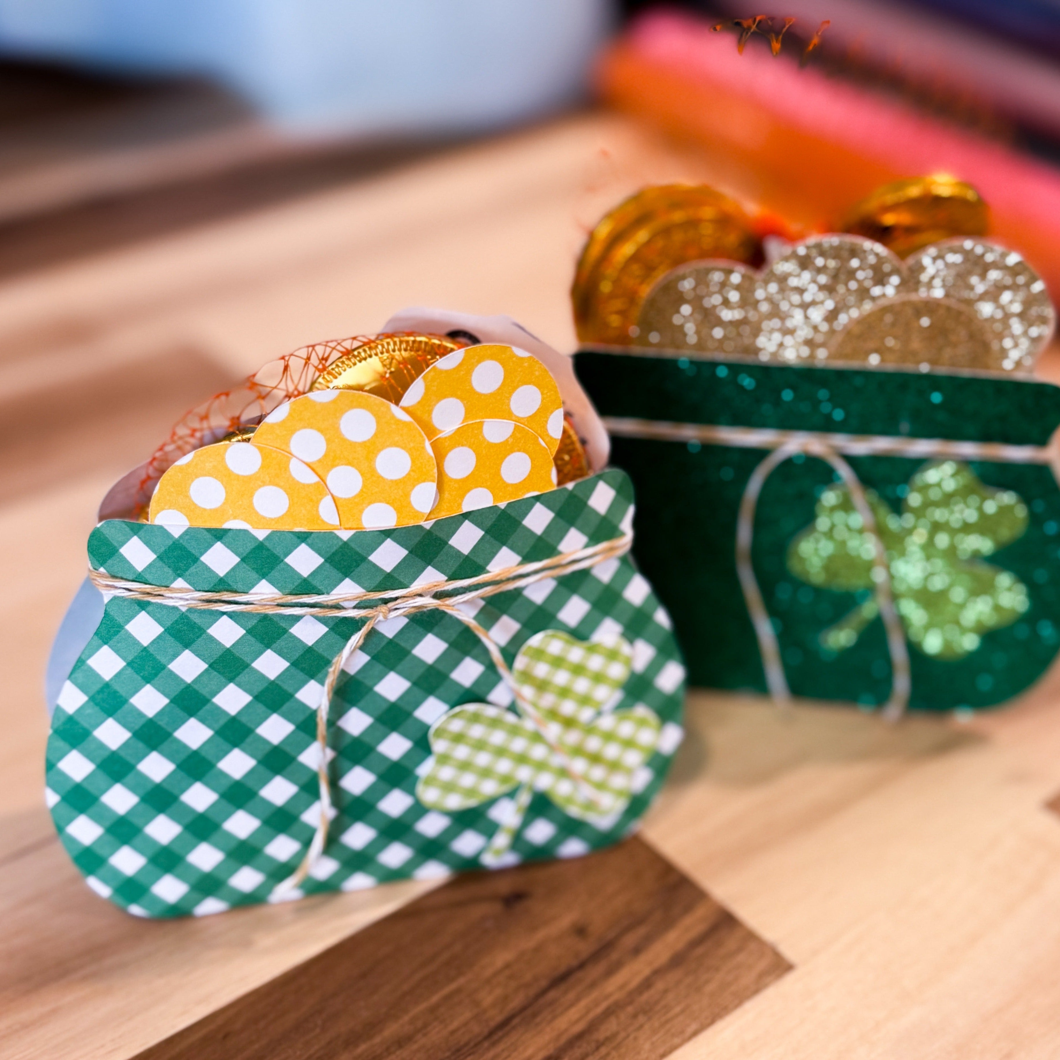 Two small green pots filled with gold coins and decorative items on a wooden surface.