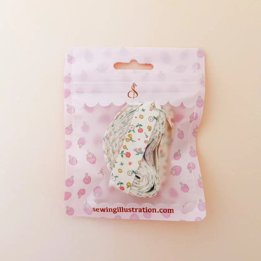 A roll of floral washi tape in a clear plastic bag with a pink strawberry-patterned backing card, displayed on a light beige background.