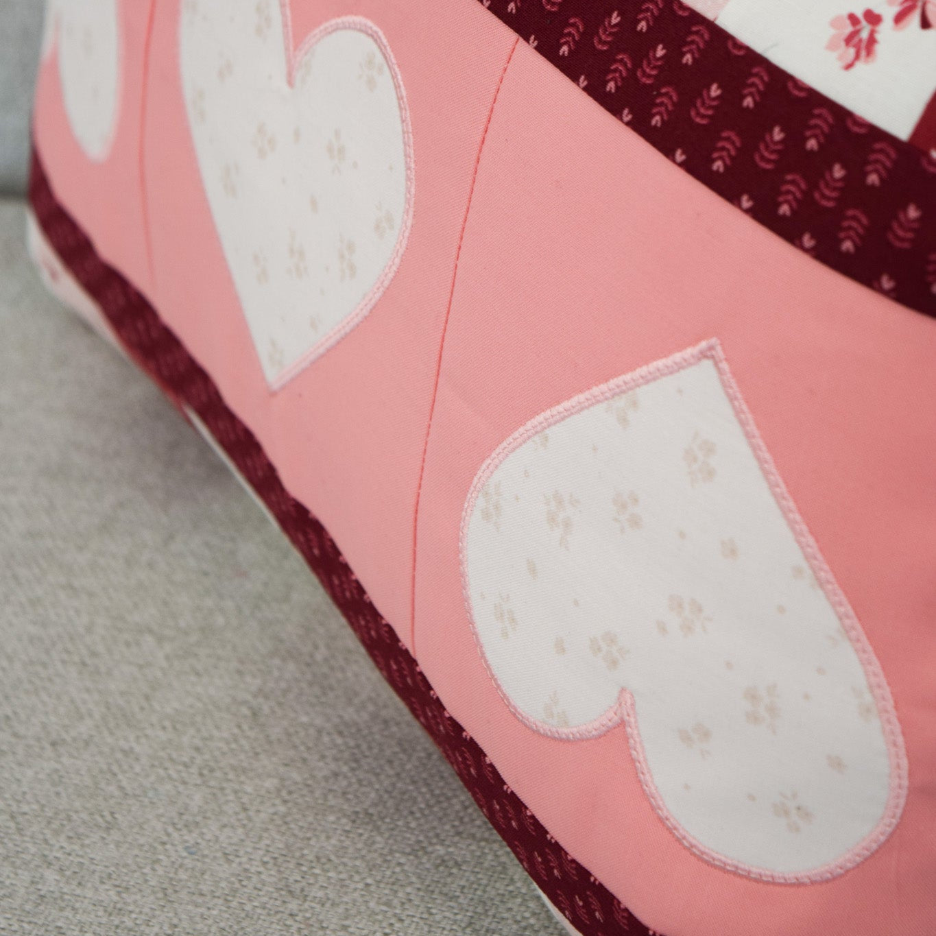 Pink slipper with heart patterns on a light gray surface