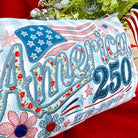 Decorative pillow with 'America 250' text and American flag design on a red background.
