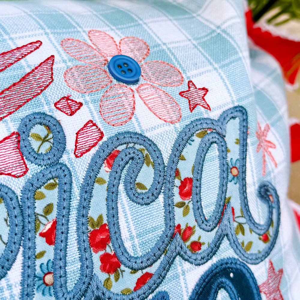 Decorative pillow with floral patterns and embroidered text on a floral background