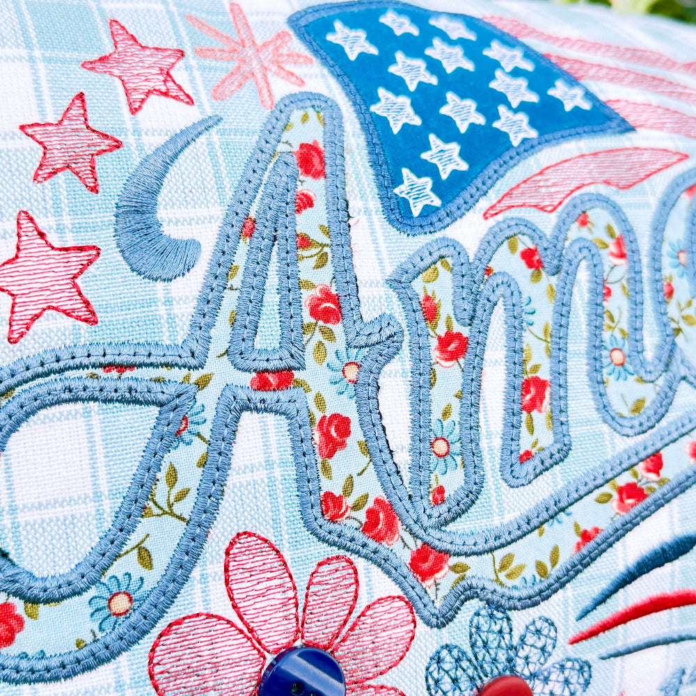 Embroidered fabric with floral and star designs, featuring the name 'Amelia'.