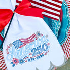 Embroidered towel with American flag design and 'America 250' text, placed on a decorative plate with a red and white checkered cloth.