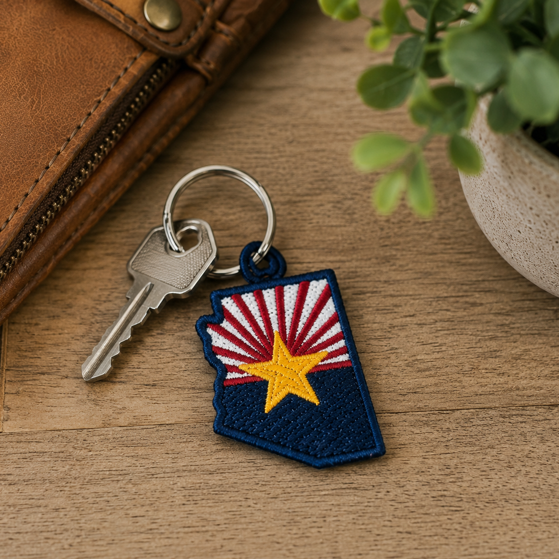 Keychain with a state-shaped design on a wooden surface with a plant in the background
