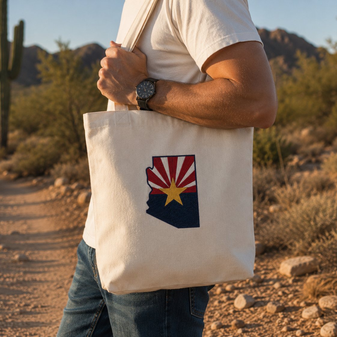 Person holding a tote bag with an Arizona state design in a desert setting