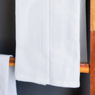 White towel hanging on a wooden rack against a dark background