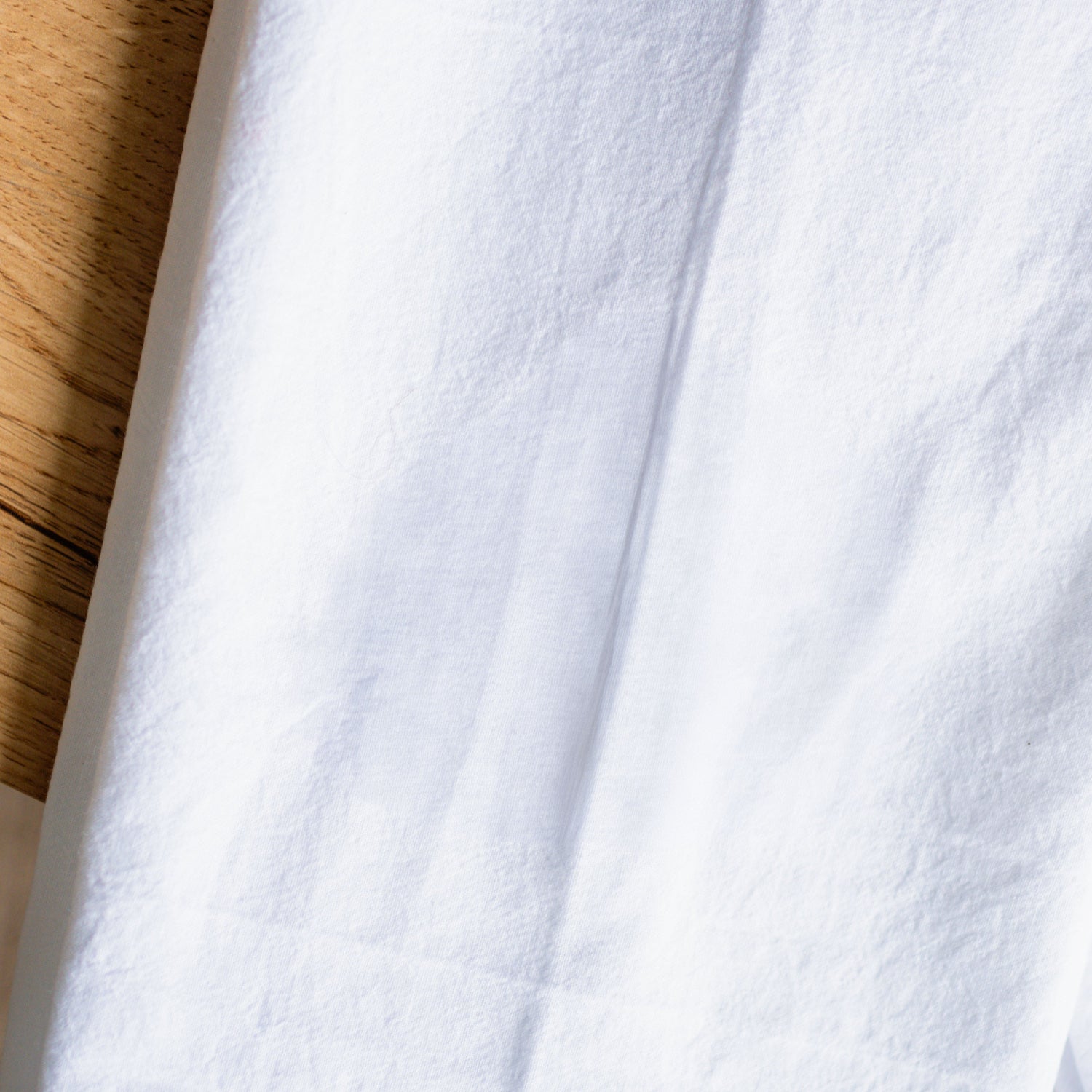 Close-up of white fabric with a wooden surface in the background