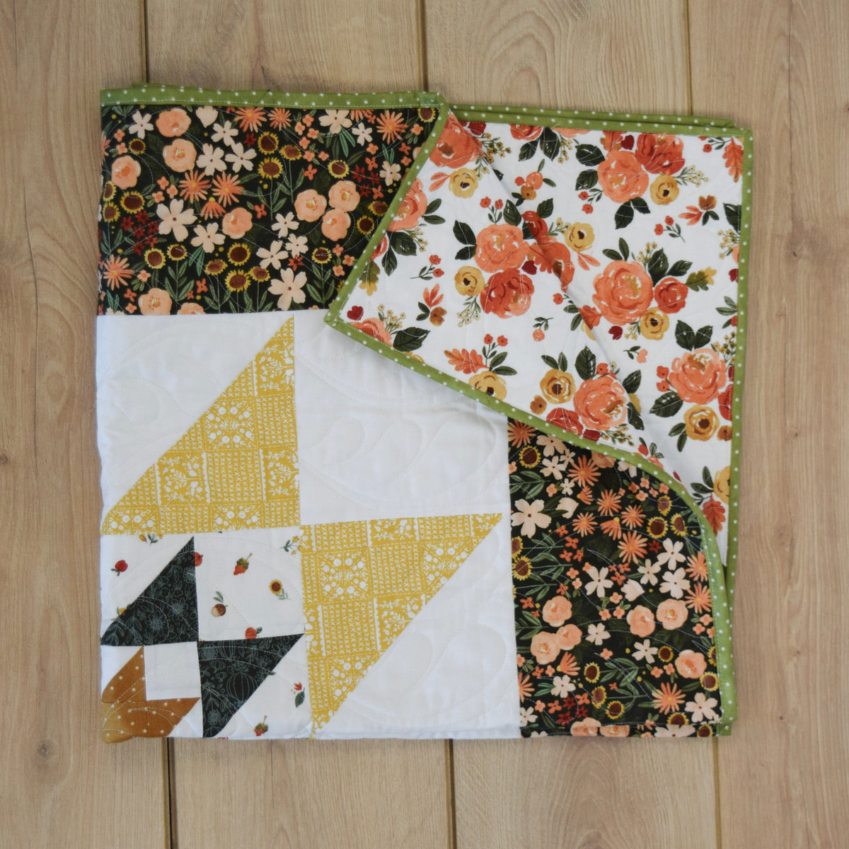 Quilted fabric squares with floral and geometric patterns on a wooden surface
