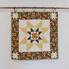 Quilt with star pattern hanging on a rack against a white background
