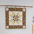 Quilt with star pattern hanging on a wall above a sofa.