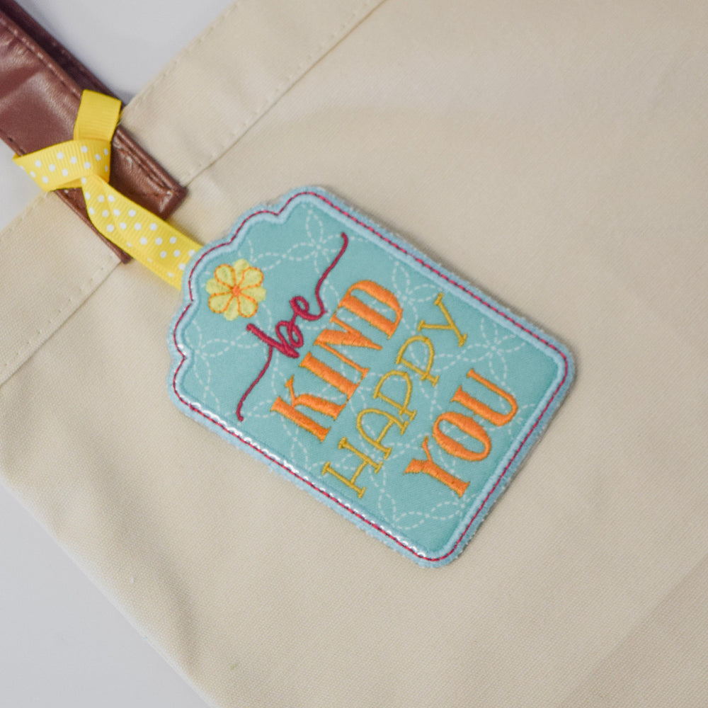 Embroidered tag on a beige bag with motivational text