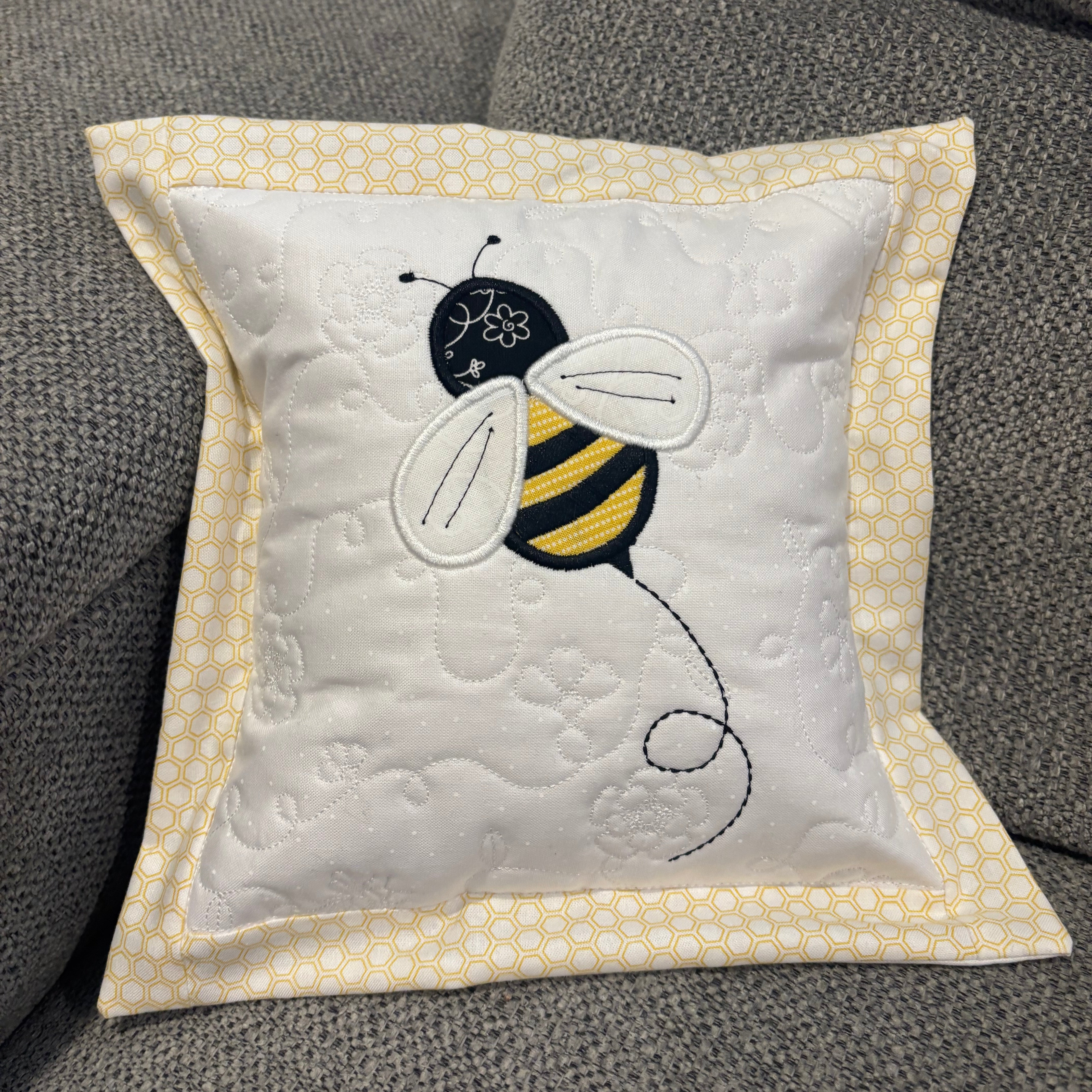 Decorative pillow with a bee design on a textured surface