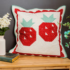 Decorative pillow with red and green patterns on a wooden surface with a dark background