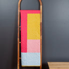 Colorful quilt on a wooden ladder against a dark wall
