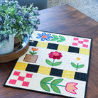 Quilt with floral patterns on a wooden table in a living room setting
