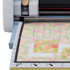 Cricut machine with a piece of floral fabric on a white background