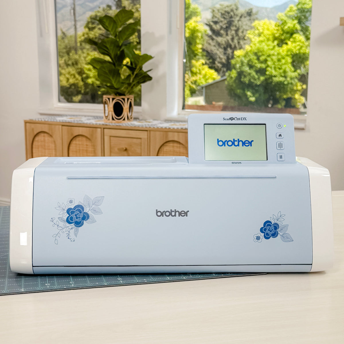 Brother crafting machine on a table with a window view of trees and sky