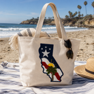Beach bag with California design on a sandy beach with ocean and palm trees in the background