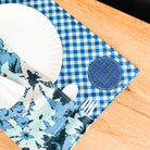 Blue and white checkered placemat with floral patterns on a wooden surface