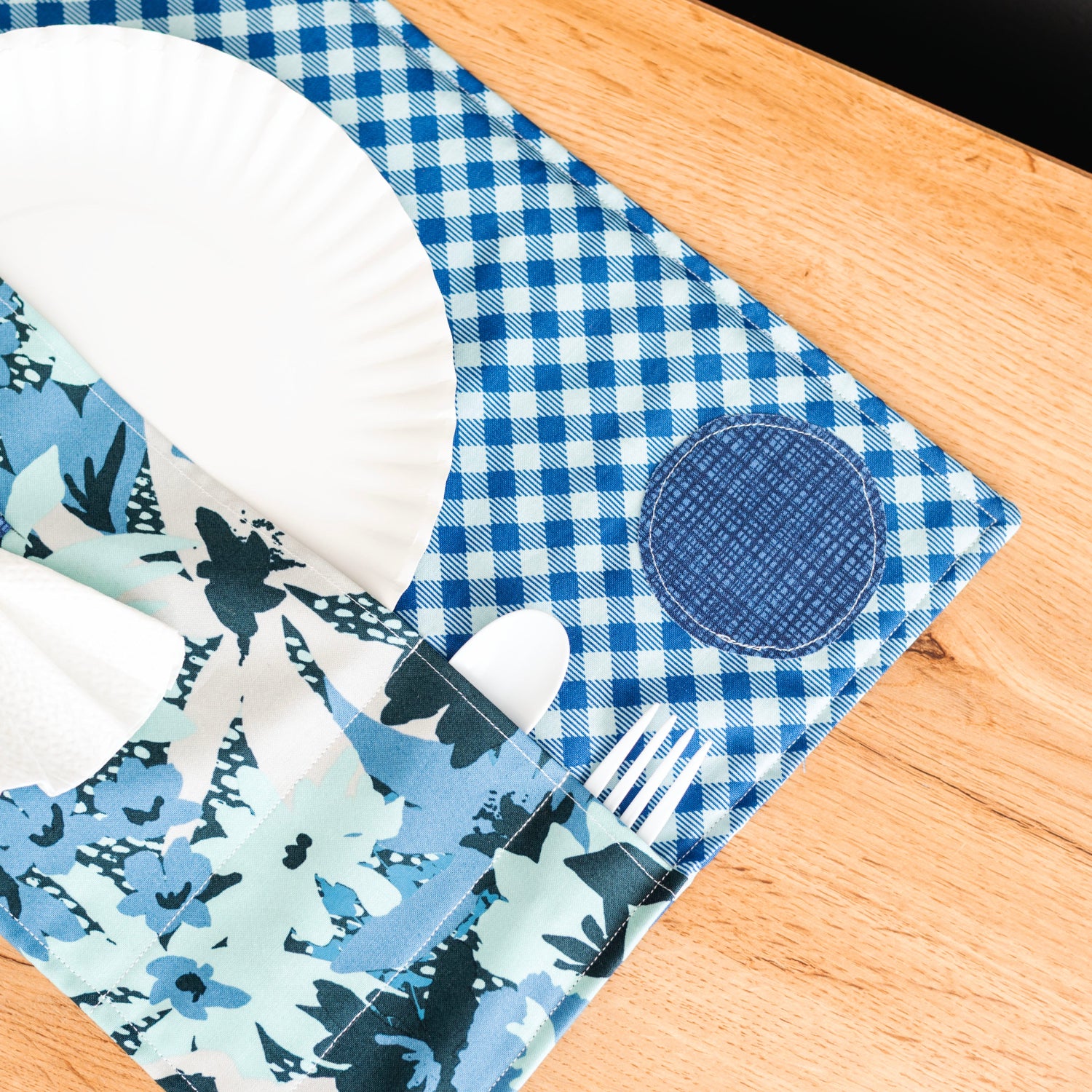 Blue and white checkered placemat with floral patterns on a wooden surface