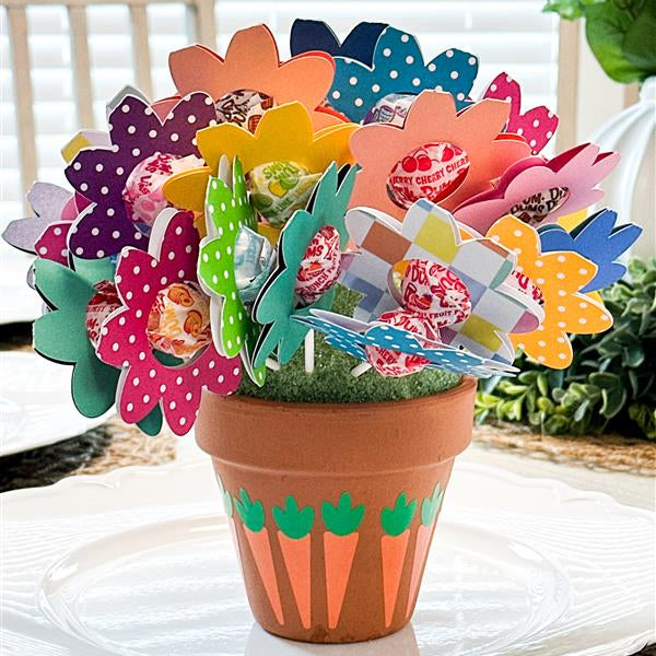 Colorful paper flowers in a terracotta pot on a white surface