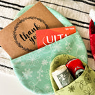 Green fabric pouch with money and a gift card on a striped surface
