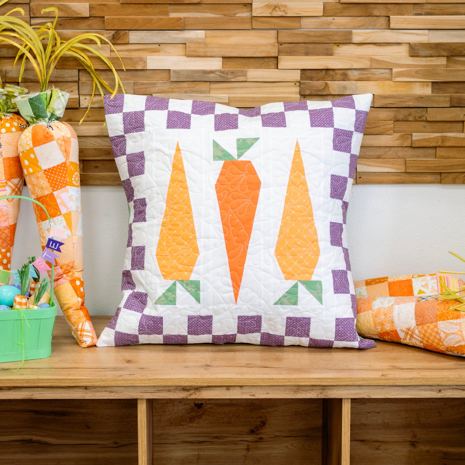 Decorative pillow with carrot design on a wooden surface against a wooden wall.