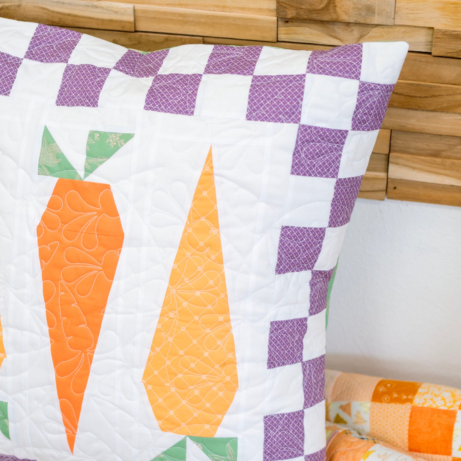 Quilted pillow with carrot design on a wooden surface
