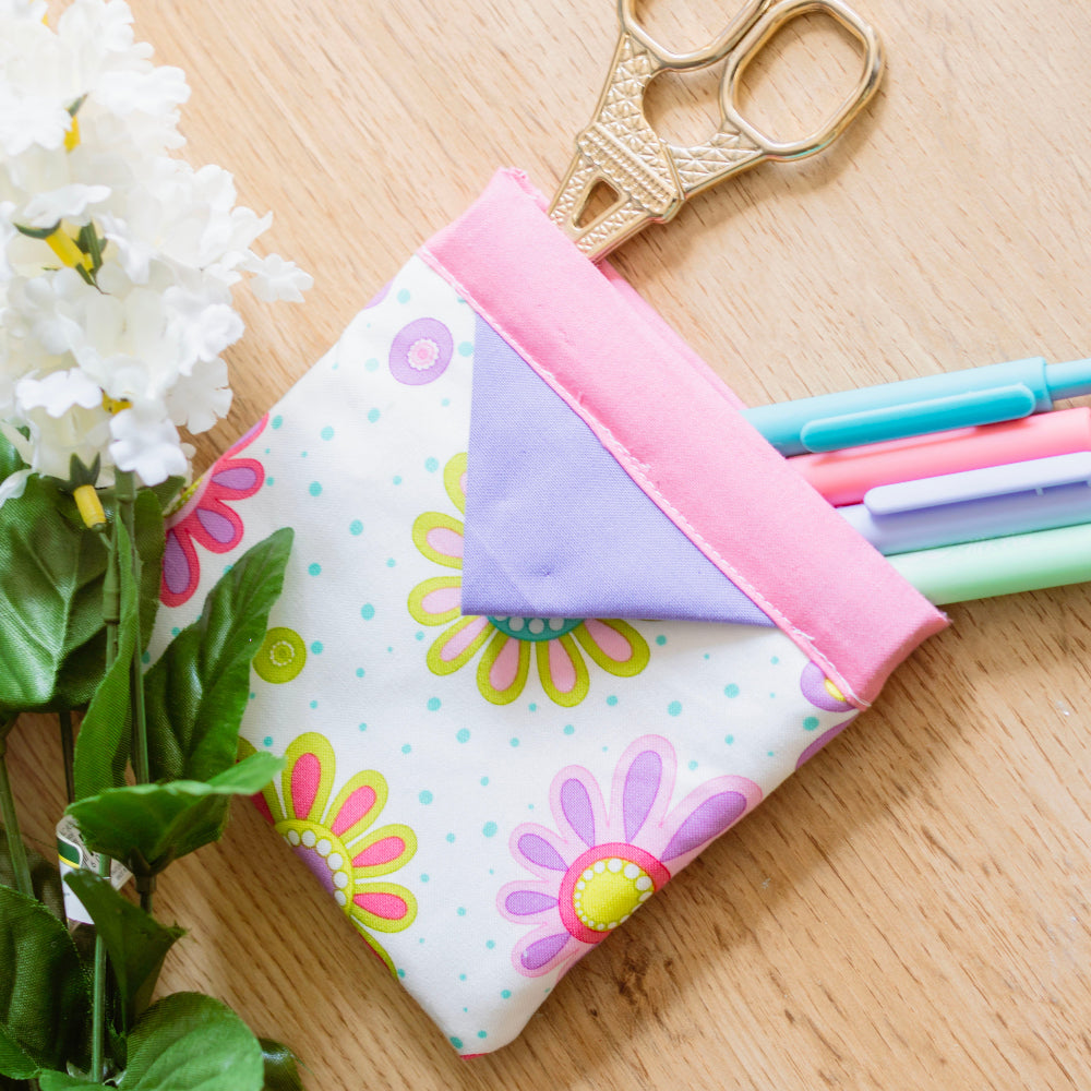 Colorful pencil case with flowers and scissors on a wooden surface