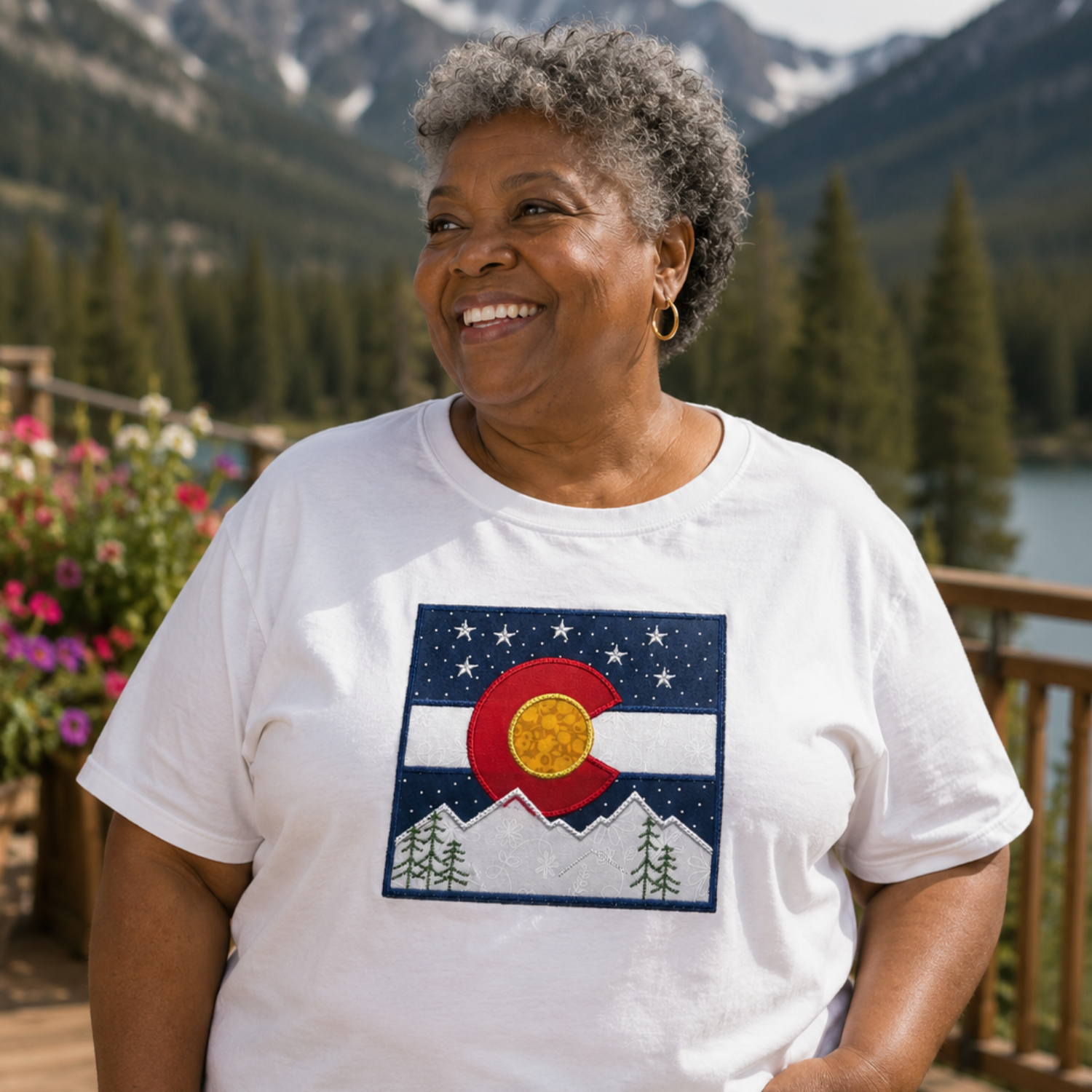 Woman wearing a white t-shirt with a Colorado flag design in a mountainous landscape.
