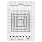 A clear acrylic quilting guide with black printed markings, concentric square patterns, and numbered stitch guides, shown on a white background.