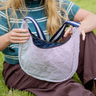 Person sitting on grass holding a striped bag