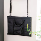 Black bag with a handle hanging on a wall-mounted hook against a white wall.