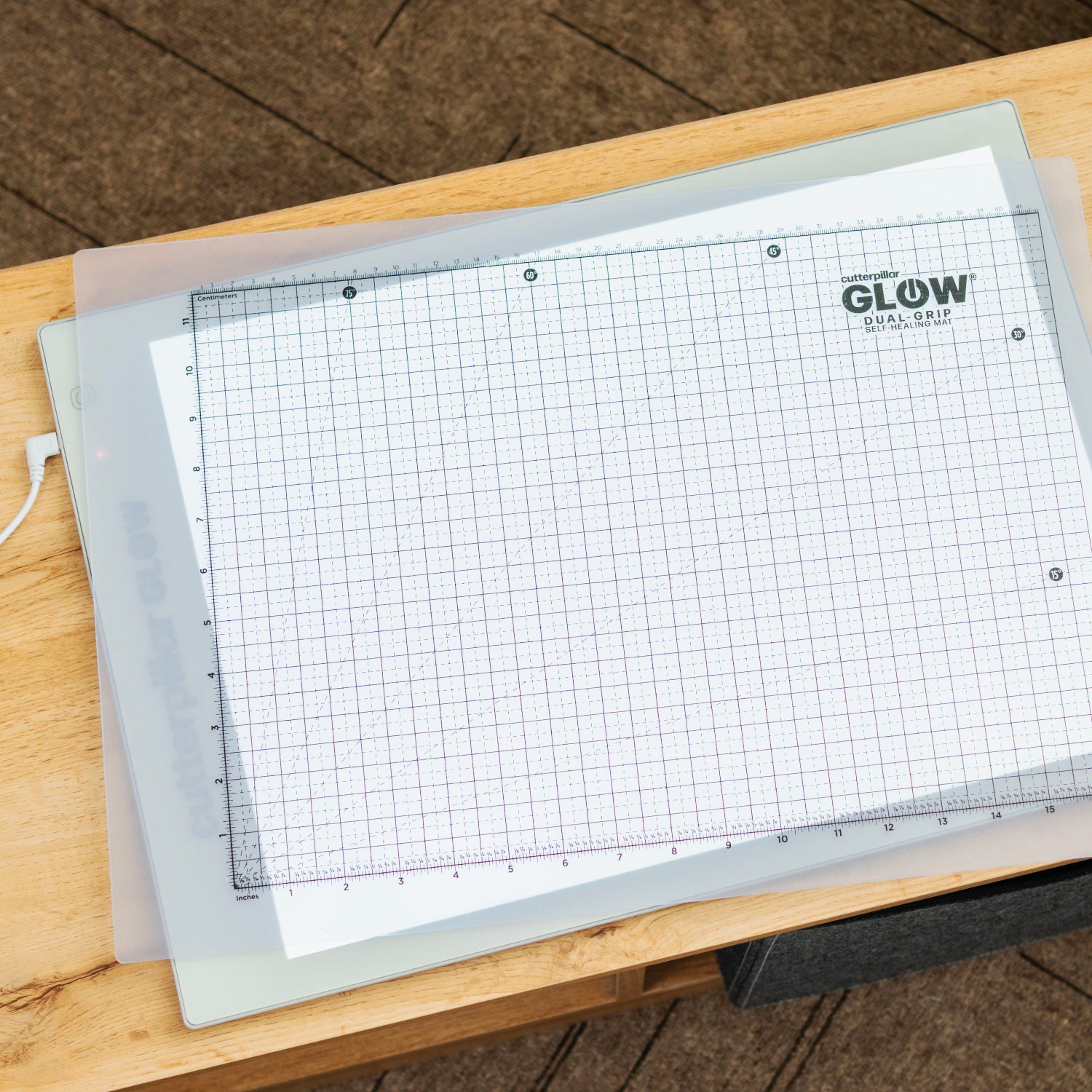 Grid cutting mat with 'Glow' branding on a wooden surface