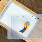 Cutterfuls Glow cutting mat with a rotary cutter on a wooden surface