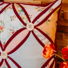 Decorative pillow with floral pattern and button details on a wooden surface.