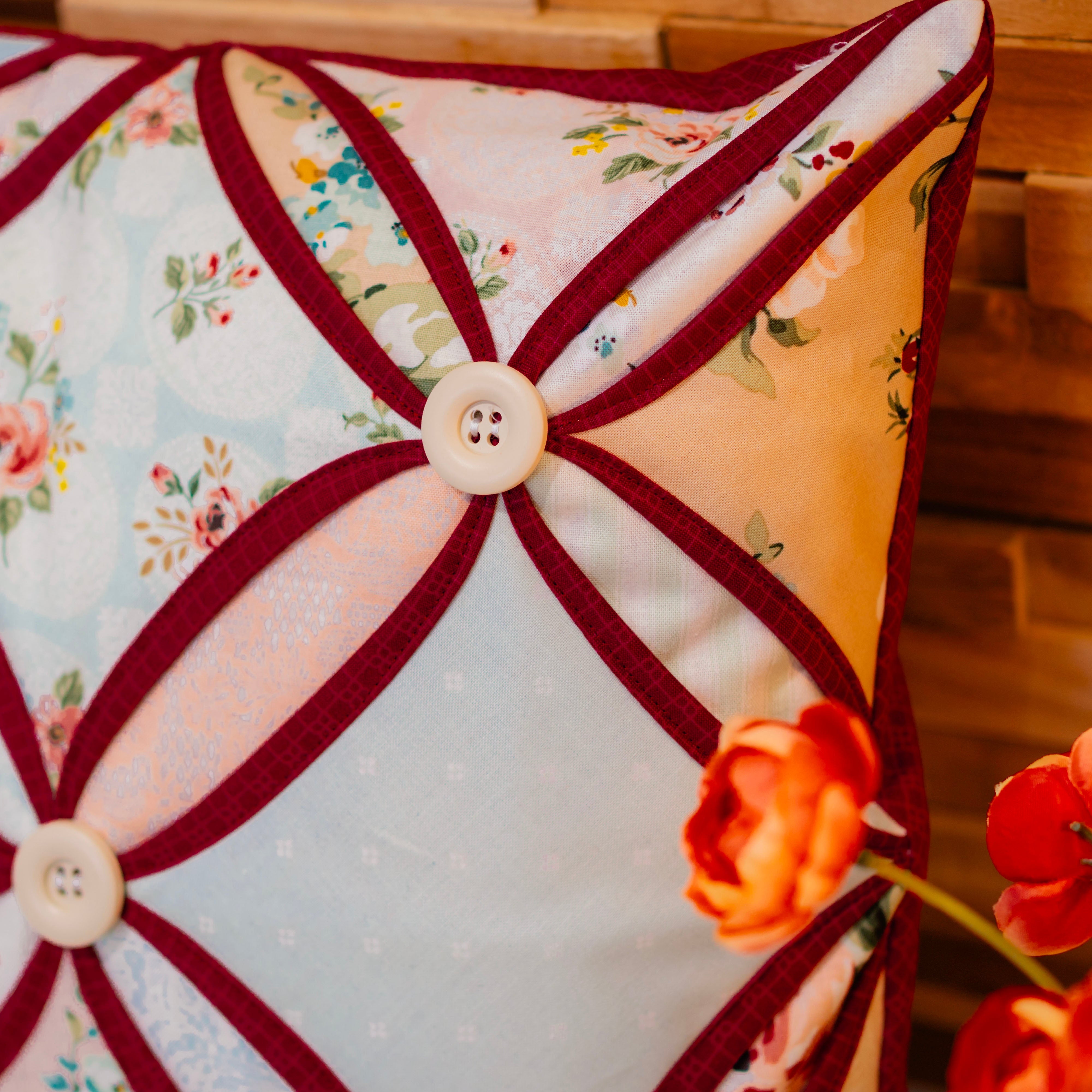 Decorative pillow with floral pattern and button details on a wooden surface.