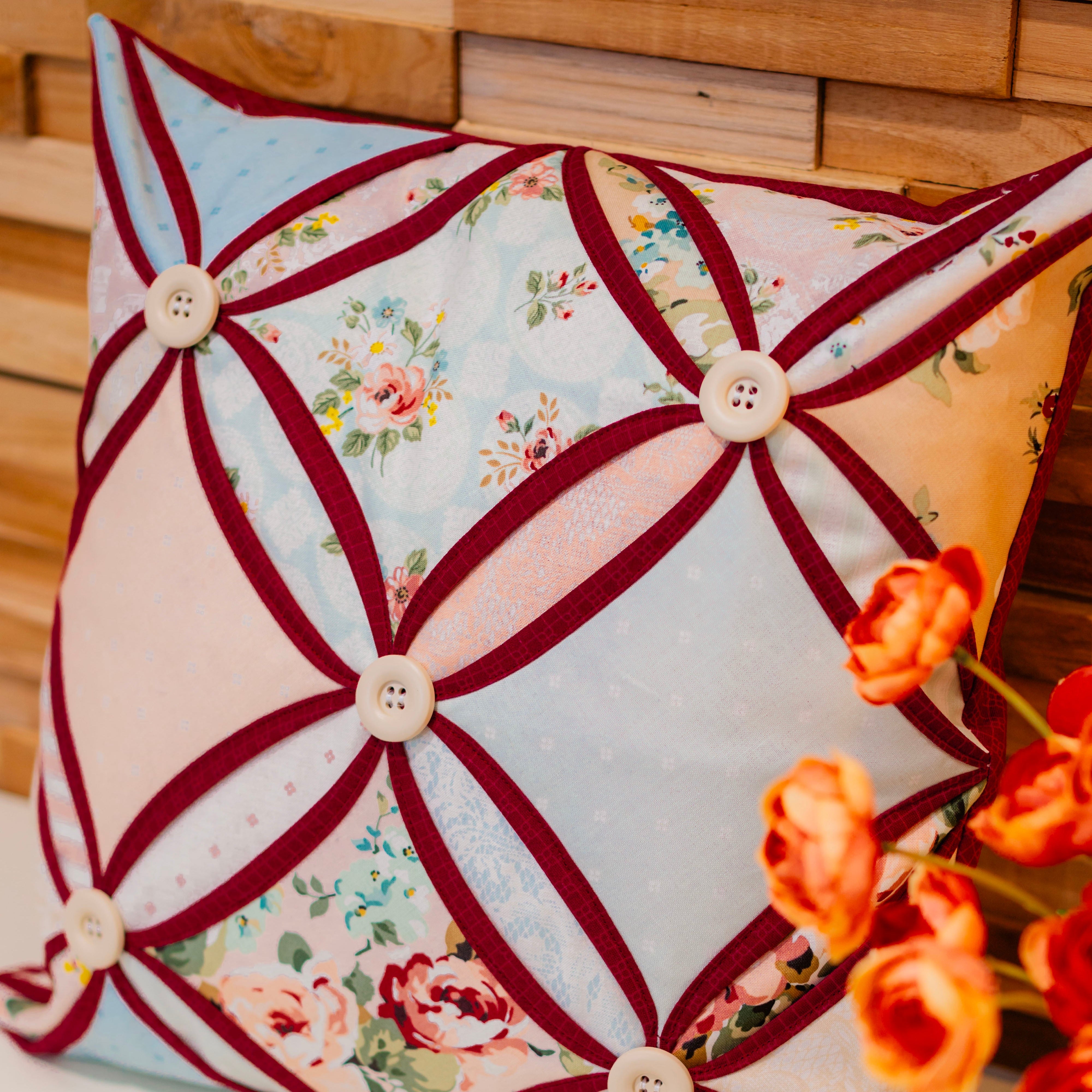 Decorative pillow with floral patterns and button details on a wooden surface.
