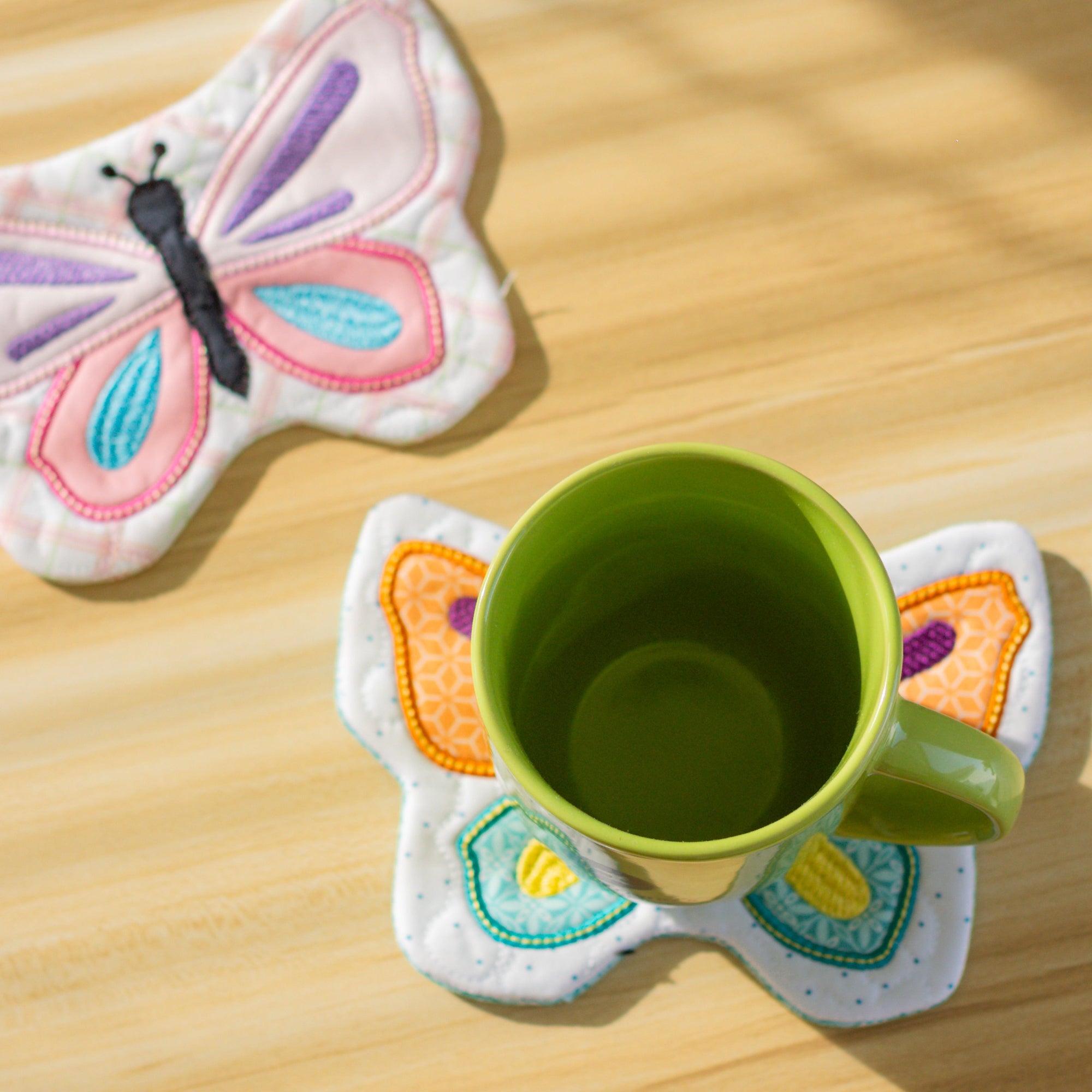 Butterfly-shaped coasters with a green mug on a wooden surface